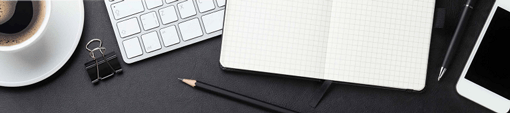 Image of desk with notebook, pencils, keyboard and coffee