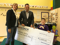 ActionCOACH members and child holding a charity cheque