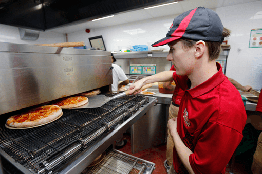 Papa John's worker cooking pizza