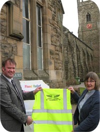 Recognition Express Cumbria owner Neal Benson presents Team rector Wendy Sanders with a Churches Together Street Angels high visibility jacket.