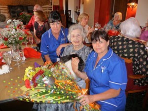 Estelle's-care-workers,-Sharon-and-Denise-presenting-her-with-her-bouquet-of-flowers-from-all-at-Caremark-(Plymouth).jpg